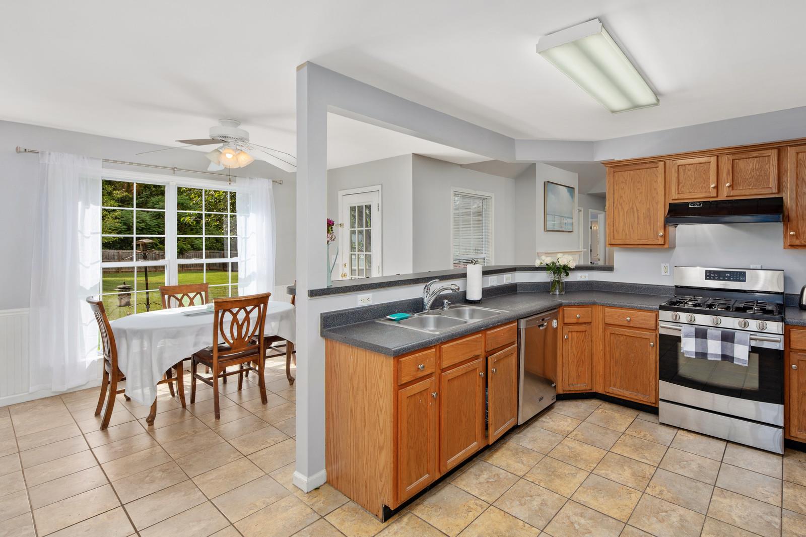 3028 Stone Bridge Road Antioch, TN 37013 - Photo 3 of 30 a kitchen with stainless steel appliances granite countertop a stove a sink a dining table and chairs