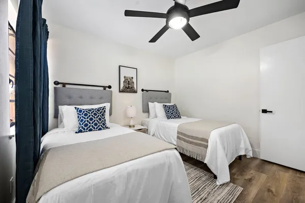 a bedroom with two beds and wooden floor
