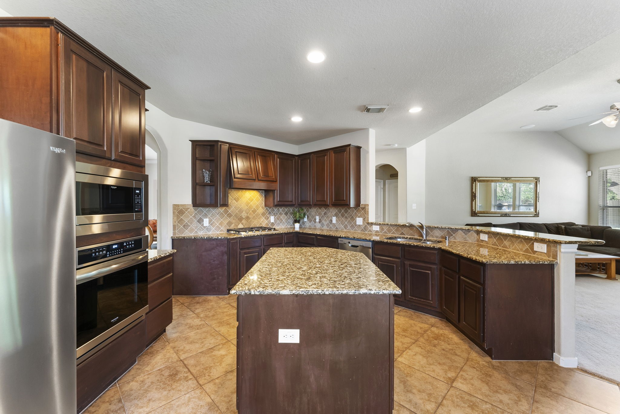 19223 Senterra Lakes Boulevard Spring, TX 77379 - Photo 24 of 48 a kitchen with stainless steel appliances granite countertop a stove top oven a sink dishwasher a dining table and chairs with wooden floor