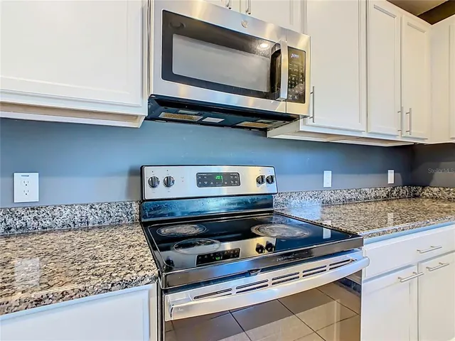 a kitchen with granite countertop a sink and white cabinets