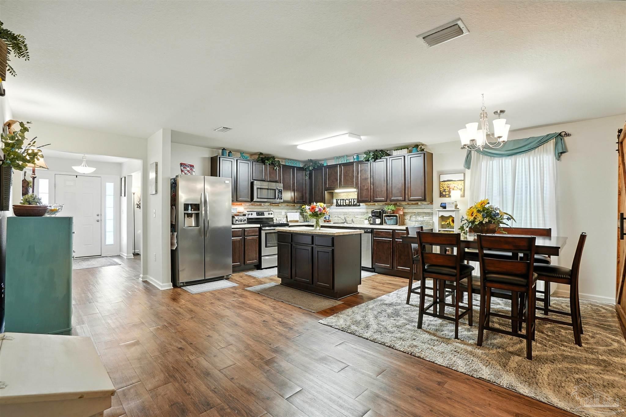 4734 Apple Field Way Pace, FL 32571 - Photo 8 of 31 a kitchen with stainless steel appliances a dining table chairs refrigerator and cabinets