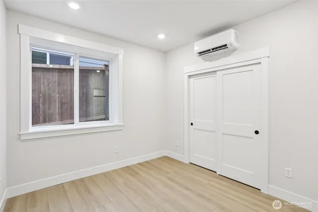 an empty room with wooden floor cabinet and windows