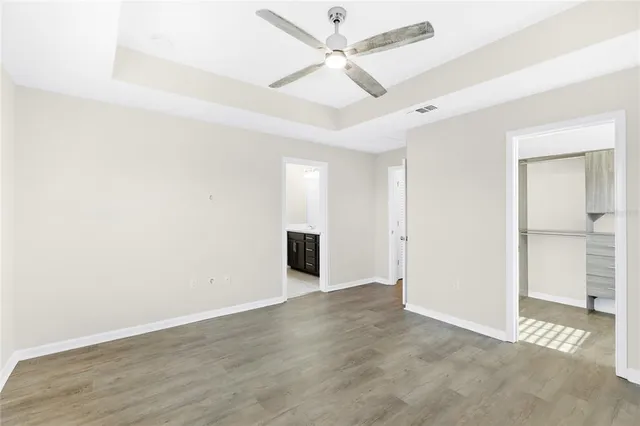 an empty room with wooden floor fan and windows