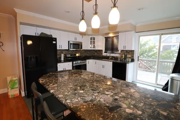 a kitchen with kitchen island granite countertop a stove a refrigerator a sink a dining table and chairs with wooden floor