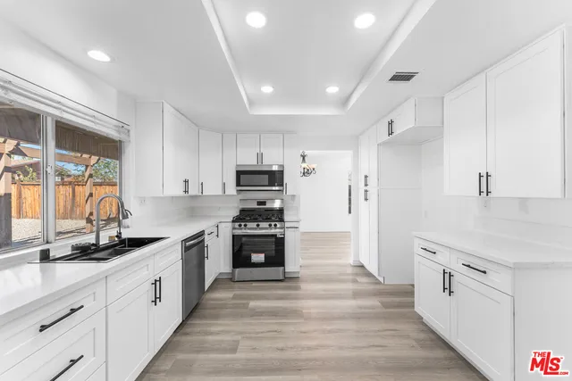 a large kitchen with stainless steel appliances and white cabinets