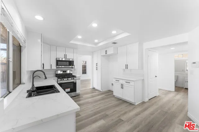 a kitchen with white cabinets and appliances