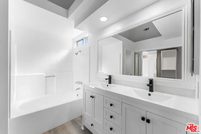 a bathroom with a double vanity sink mirror and bathtub