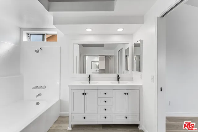 a spacious bathroom with a double vanity sink a mirror and a bathtub