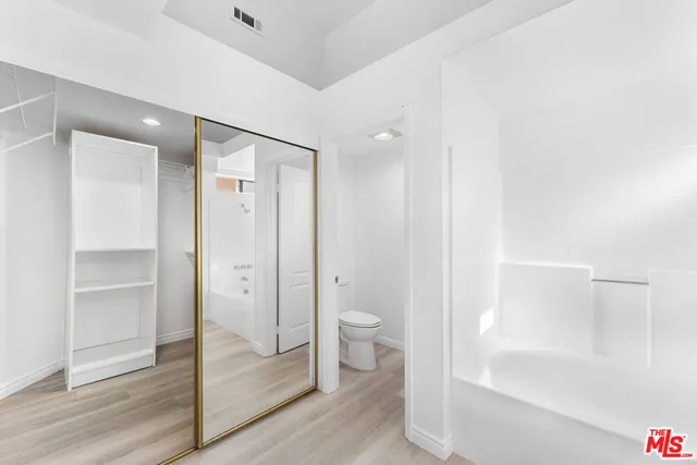 a bathroom with a tub sink toilet and a large mirror