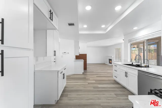 a large white kitchen with a lot of counter space and wooden floor
