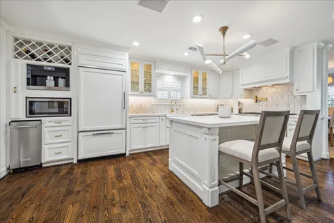 a kitchen with stainless steel appliances kitchen island granite countertop a sink cabinets and wooden floor