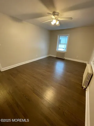 an empty room with wooden floor fan and windows