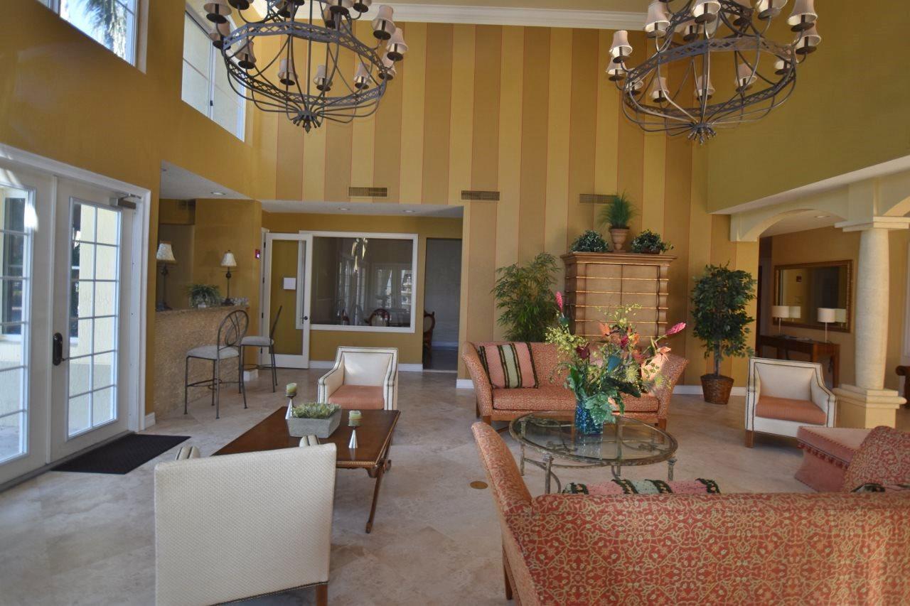 11016 Legacy Drive, Unit 103 Palm Beach Gardens, FL 33410 - Photo 44 of 44 a living room with fireplace furniture and a chandelier