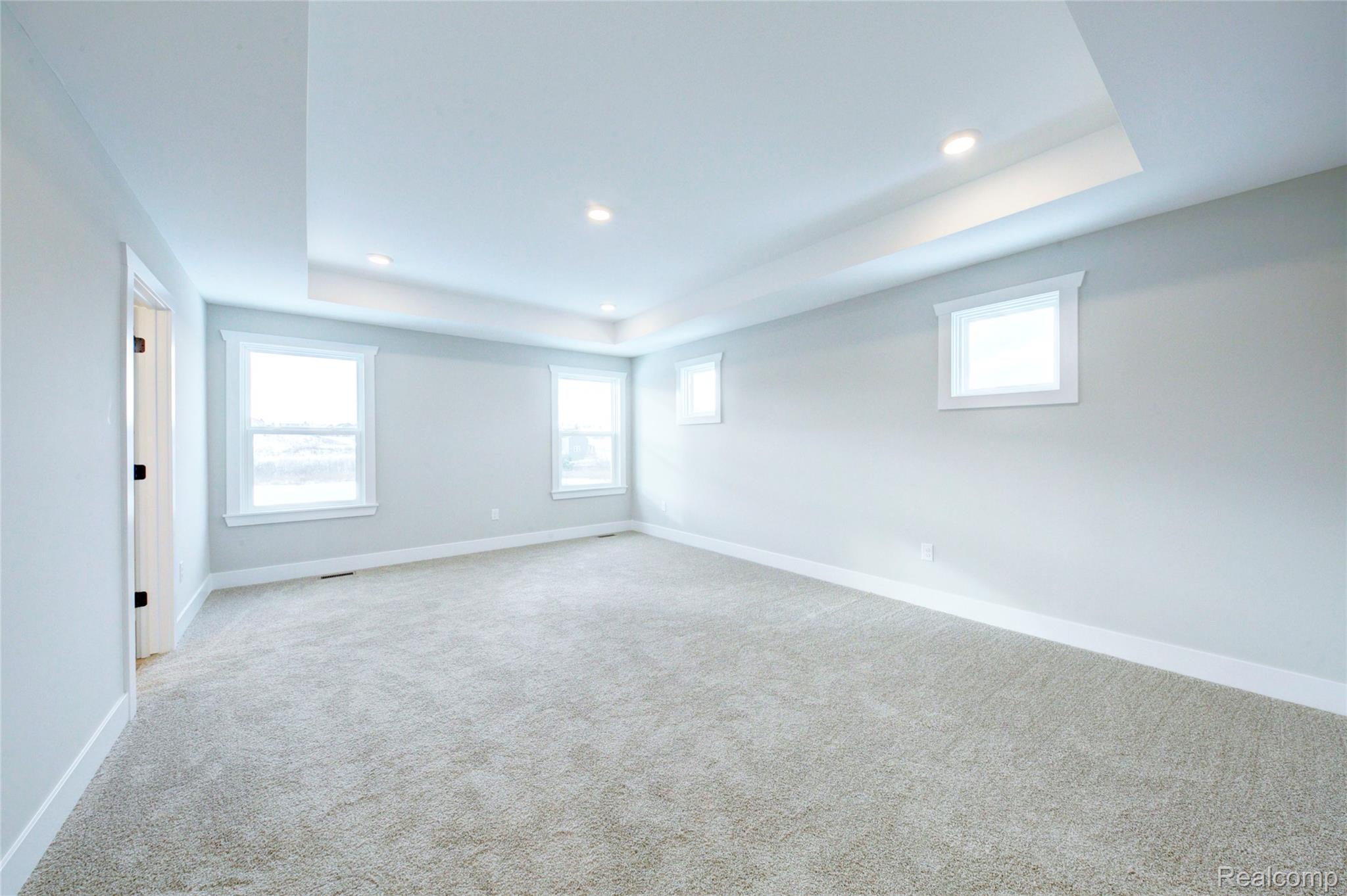 579 Round Rock (moh80) Howell, MI 48843 - Photo 15 of 42 Unfurnished room featuring a tray ceiling, recessed lighting, and light carpet