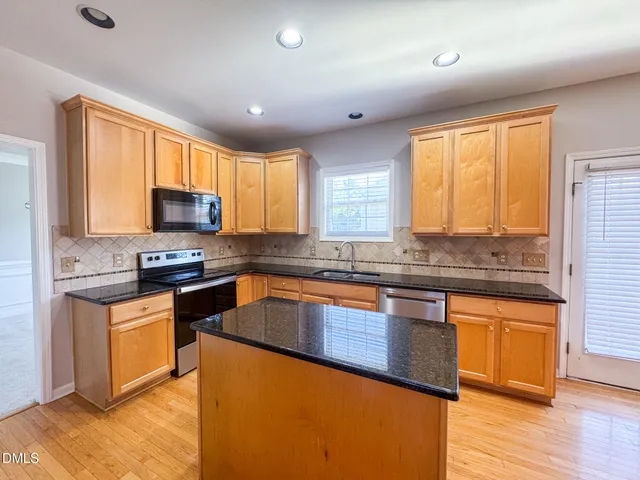 a kitchen with stainless steel appliances granite countertop a stove a sink and a microwave