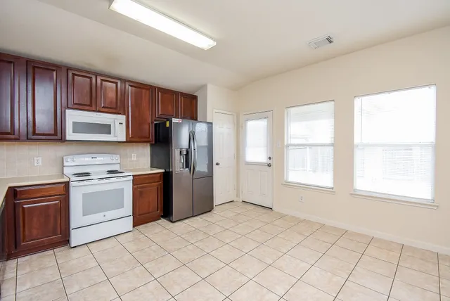 a kitchen with a refrigerator a stove top oven cabinets and a window