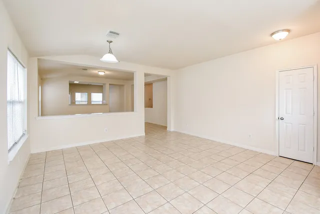 an empty room with kitchen view and windows
