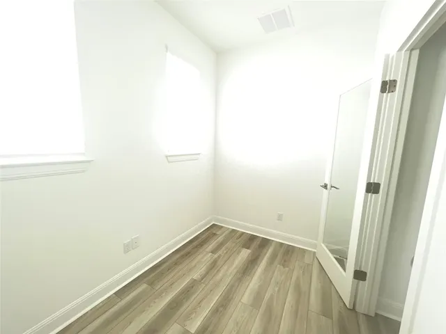 a view of a hallway with wooden floor and closet area