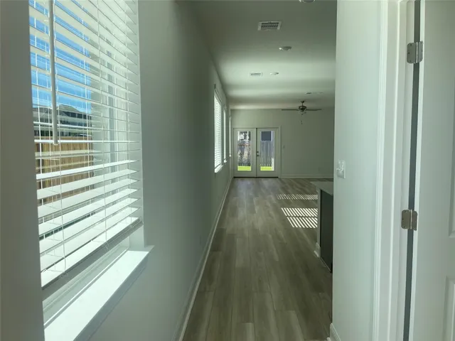 a view of a hallway with wooden floor and a bathroom