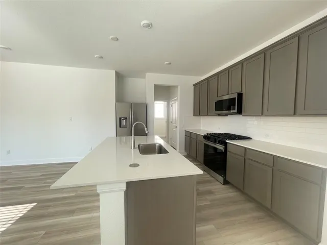 a large kitchen with stainless steel appliances granite countertop a lot of counter space and wooden floors