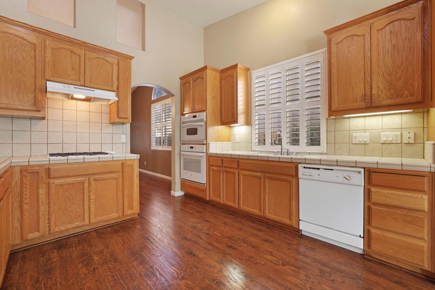 4316 Versailles Drive Modesto, CA 95356 - Photo 11 of 45 a kitchen with stainless steel appliances wooden floors and wooden cabinets
