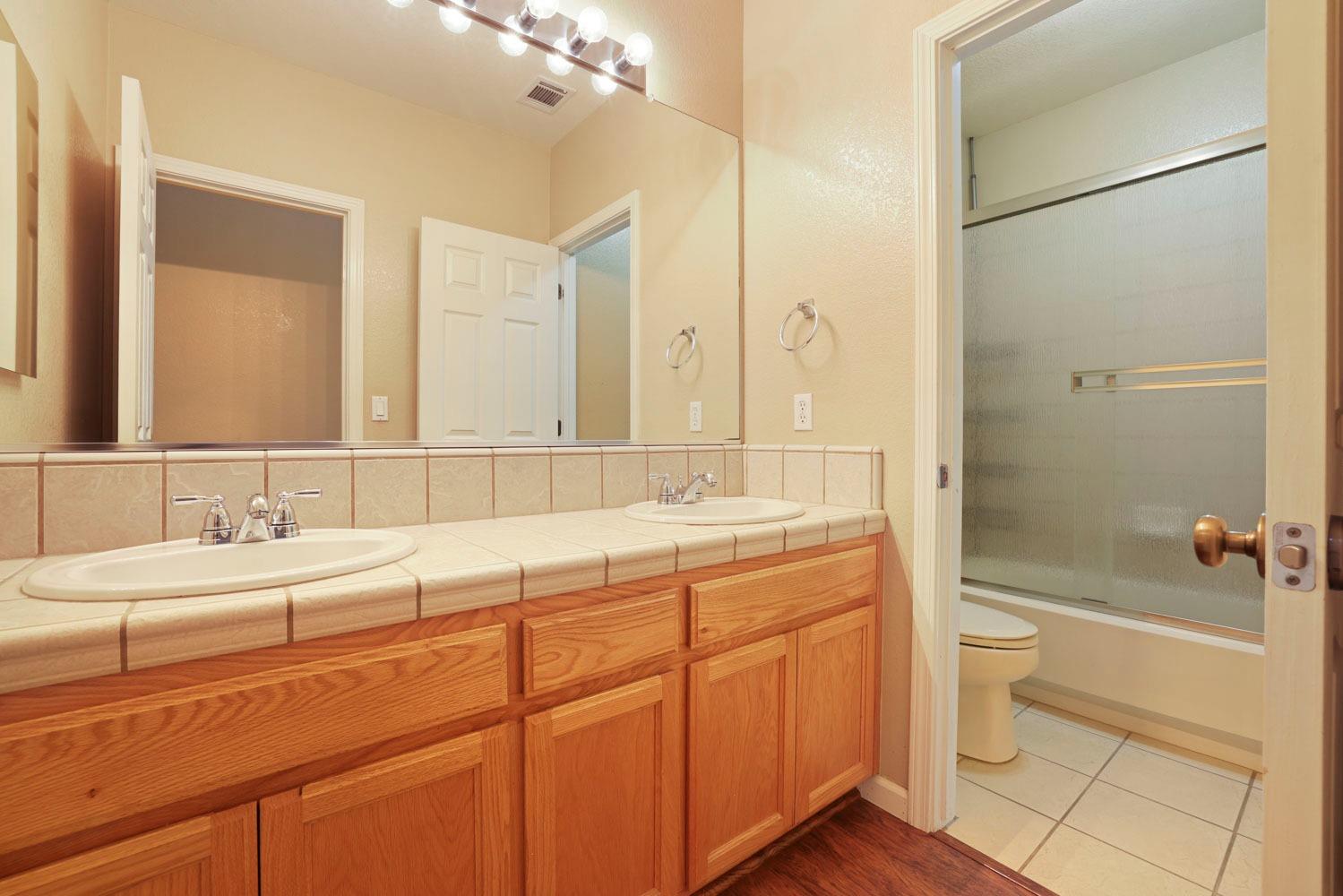 4316 Versailles Drive Modesto, CA 95356 - Photo 20 of 45 a bathroom with a double vanity sink toilet mirror and shower