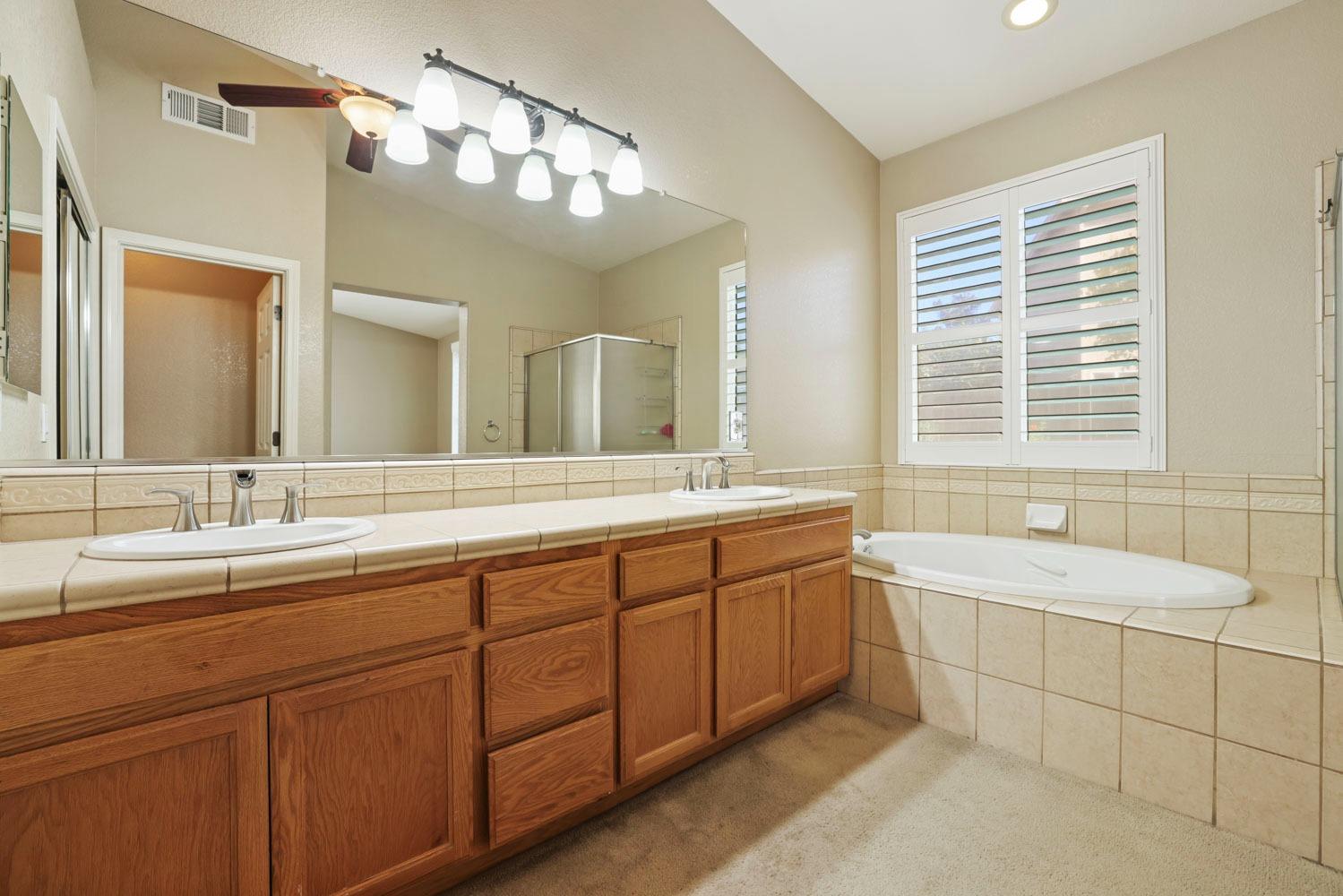 4316 Versailles Drive Modesto, CA 95356 - Photo 27 of 45 a spacious bathroom with a double vanity sink large mirror and a bathtub