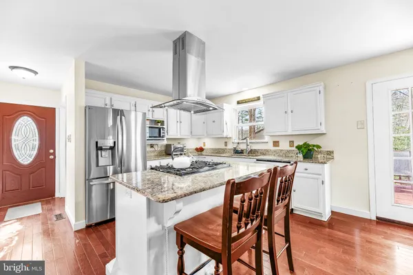 a kitchen with stainless steel appliances granite countertop a kitchen island a stove a table and chairs in it