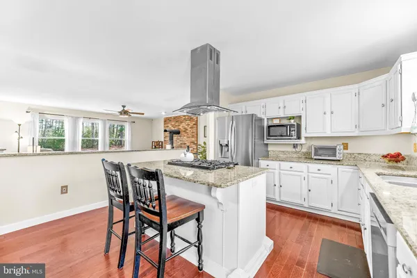 a kitchen with stainless steel appliances kitchen island granite countertop a table chairs in it and white cabinets