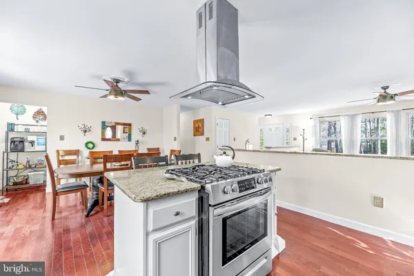 a kitchen with stainless steel appliances granite countertop a stove and a wooden floors