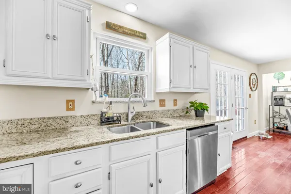 a kitchen with granite countertop a sink stainless steel appliances and cabinets