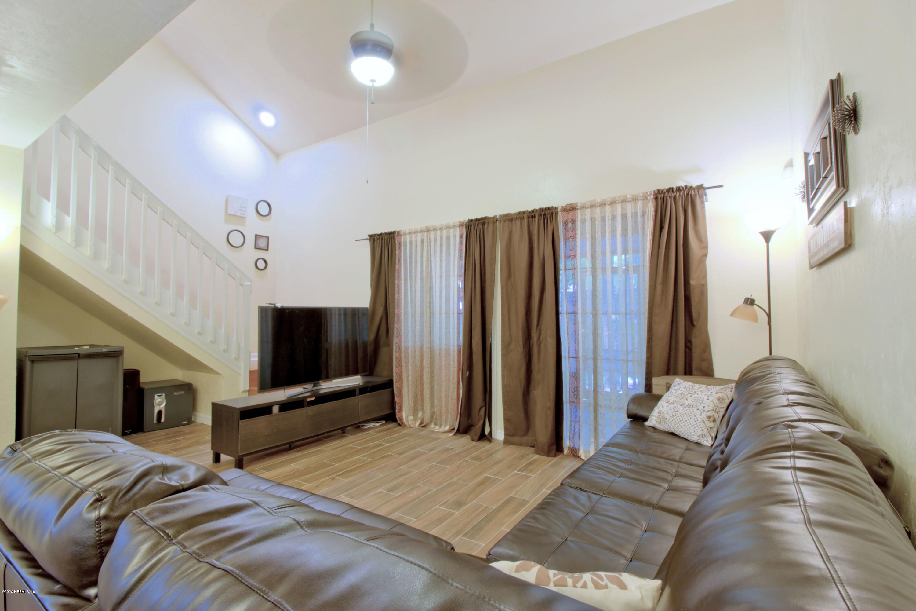 910 Southwest 57 Terrace Gainesville, FL 32607 - Photo 15 of 18 a bedroom with a bed tv and a chandelier