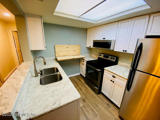 910 Southwest 57 Terrace Gainesville, FL 32607 - Photo 3 of 18 a kitchen with granite countertop a sink a stove a refrigerator and cabinets