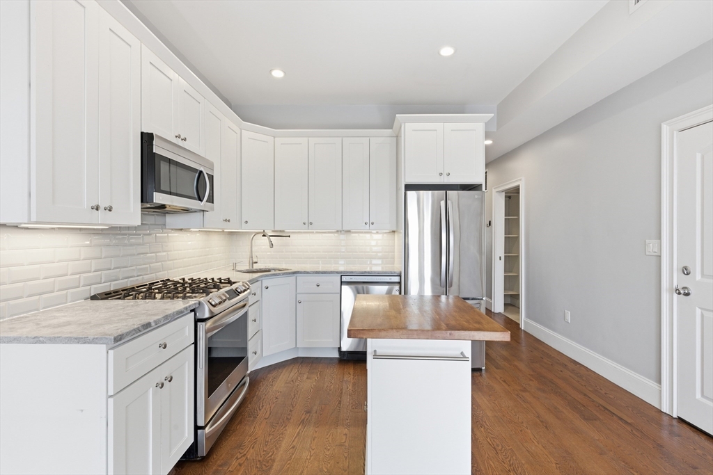 249 Lexington Street, Unit 2 Boston, MA 02128 - Photo 6 of 24 a kitchen with granite countertop a stove top oven a sink dishwasher and a refrigerator with wooden floor