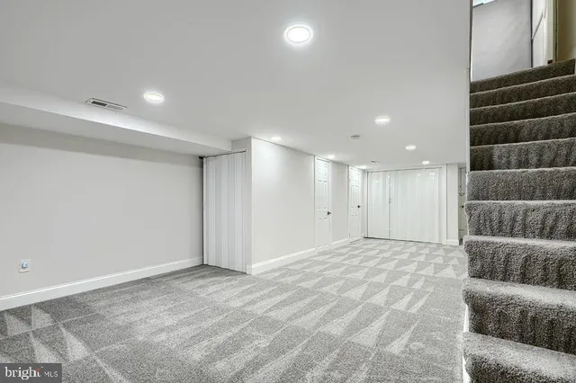 a view of an empty room with wooden floor and stairs