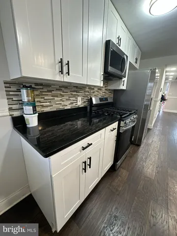 a kitchen with granite countertop stainless steel appliances a stove microwave and wooden floor