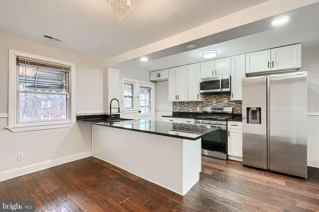 a kitchen with kitchen island granite countertop a sink cabinets and stainless steel appliances