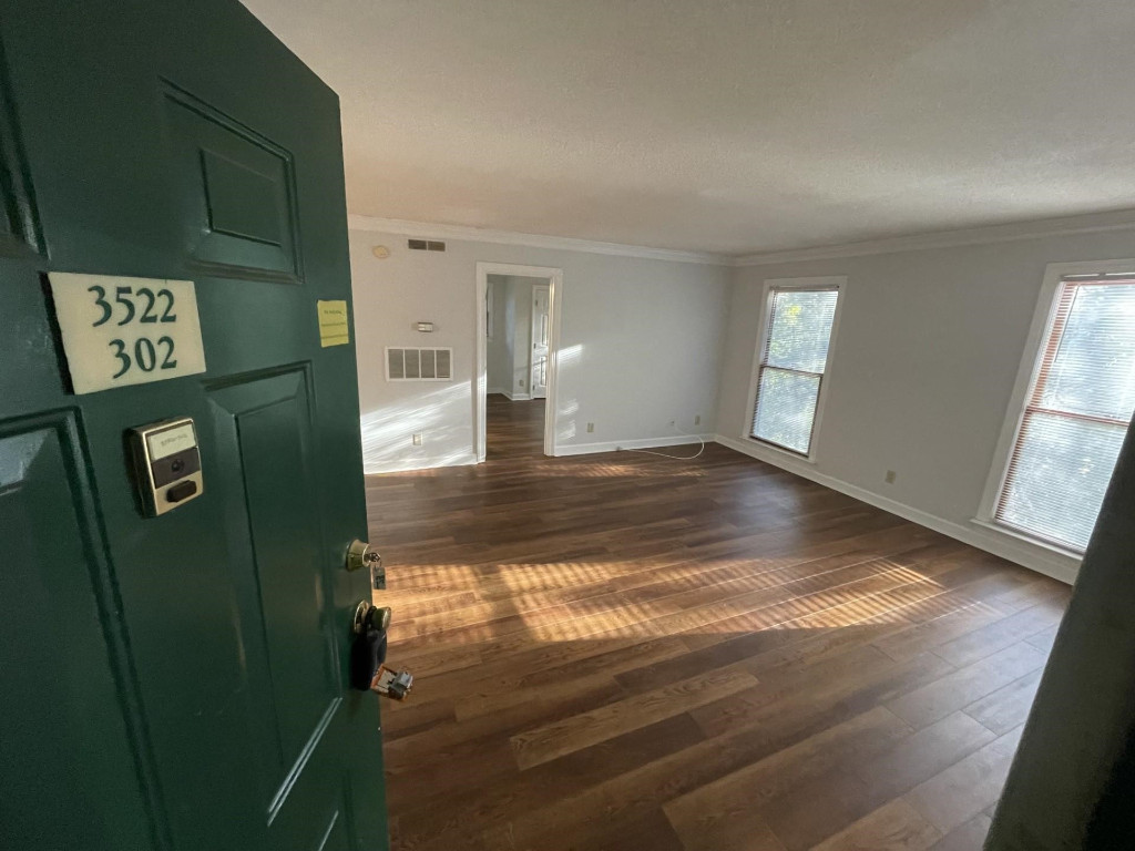 a view of a hallway to a bedroom with wooden floor and windows