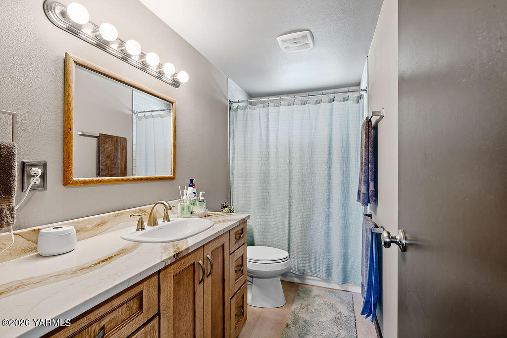 3003 South 79th Avenue Yakima, WA 98903 - Photo 21 of 32 a bathroom with a granite countertop sink toilet a mirror a vanity and shower