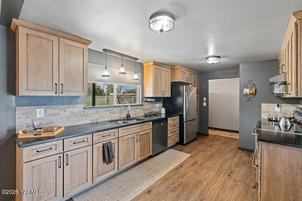 3003 South 79th Avenue Yakima, WA 98903 - Photo 7 of 32 a kitchen with stainless steel appliances granite countertop a refrigerator a sink dishwasher a stove and white cabinets with wooden floor