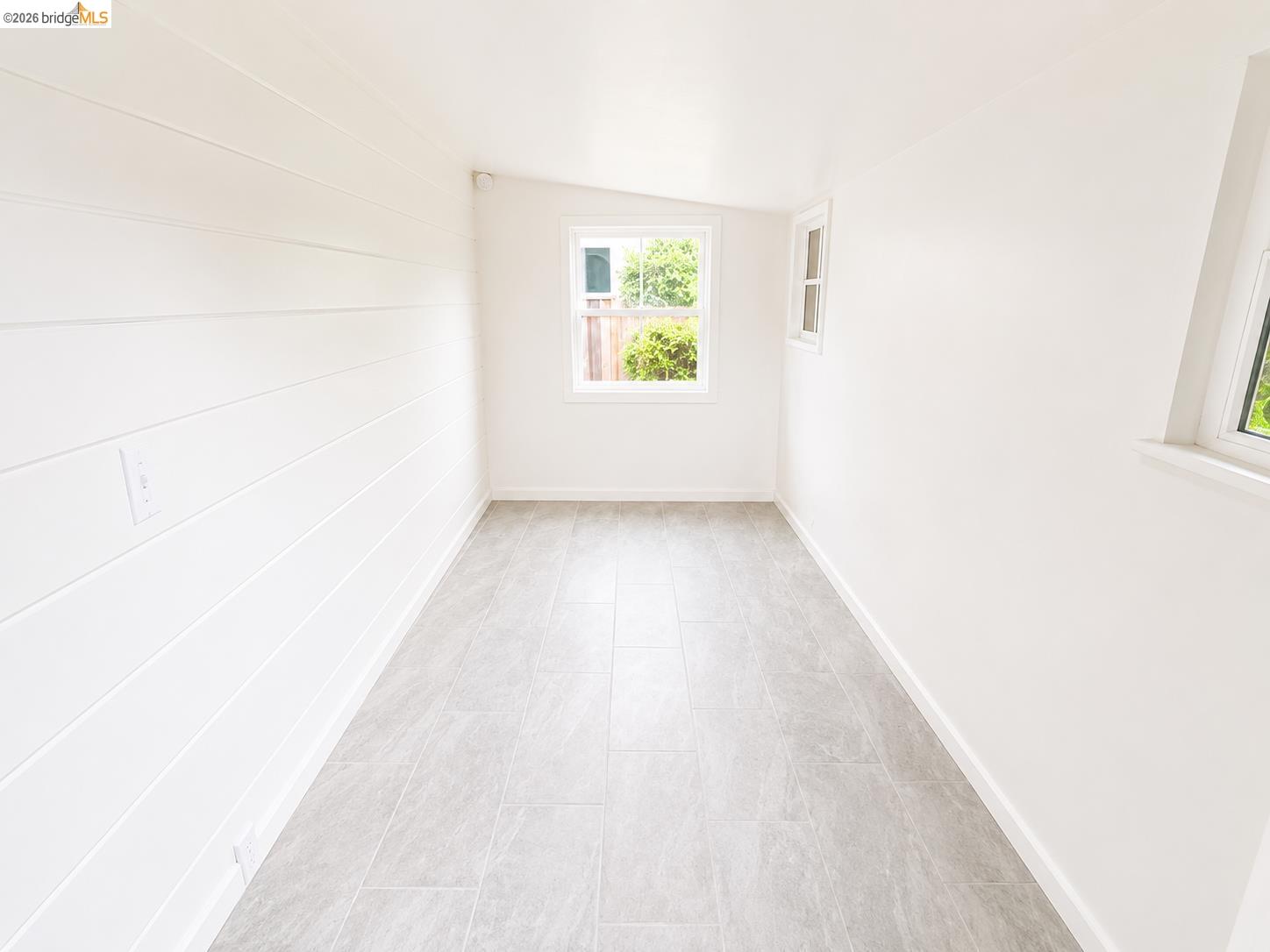810 Pierce Street Albany, CA 94706 - Photo 21 of 25 Light-filled interior space featuring three windows, white walls, and light gray tile flooring