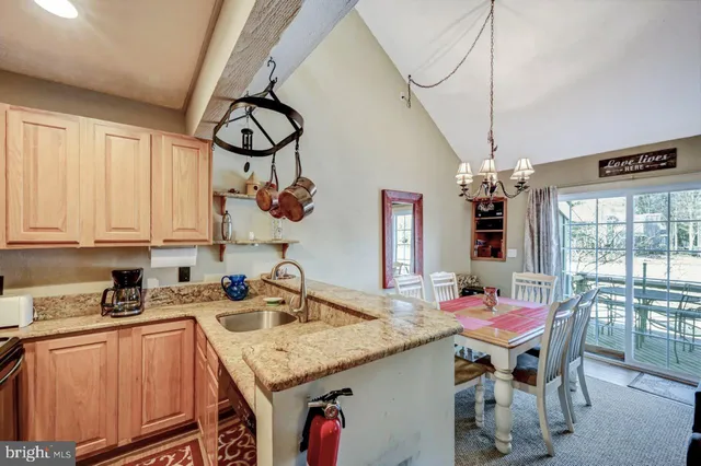 a kitchen with stainless steel appliances granite countertop a sink a stove and chairs with wooden floor