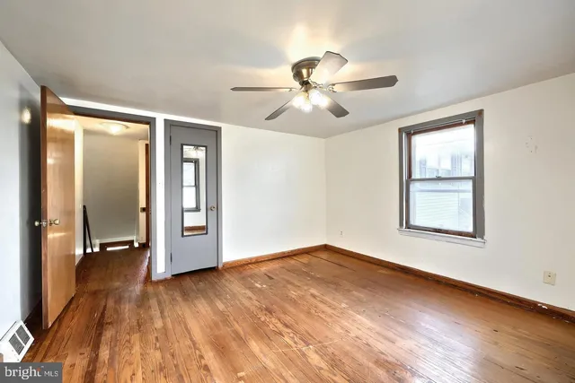 a view of empty room with wooden floor and fan