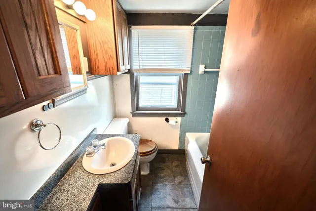 a bathroom with a granite countertop sink toilet and a mirror