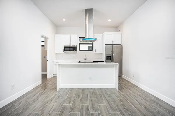 a kitchen with stainless steel appliances granite countertop a sink a microwave a refrigerator and white cabinets