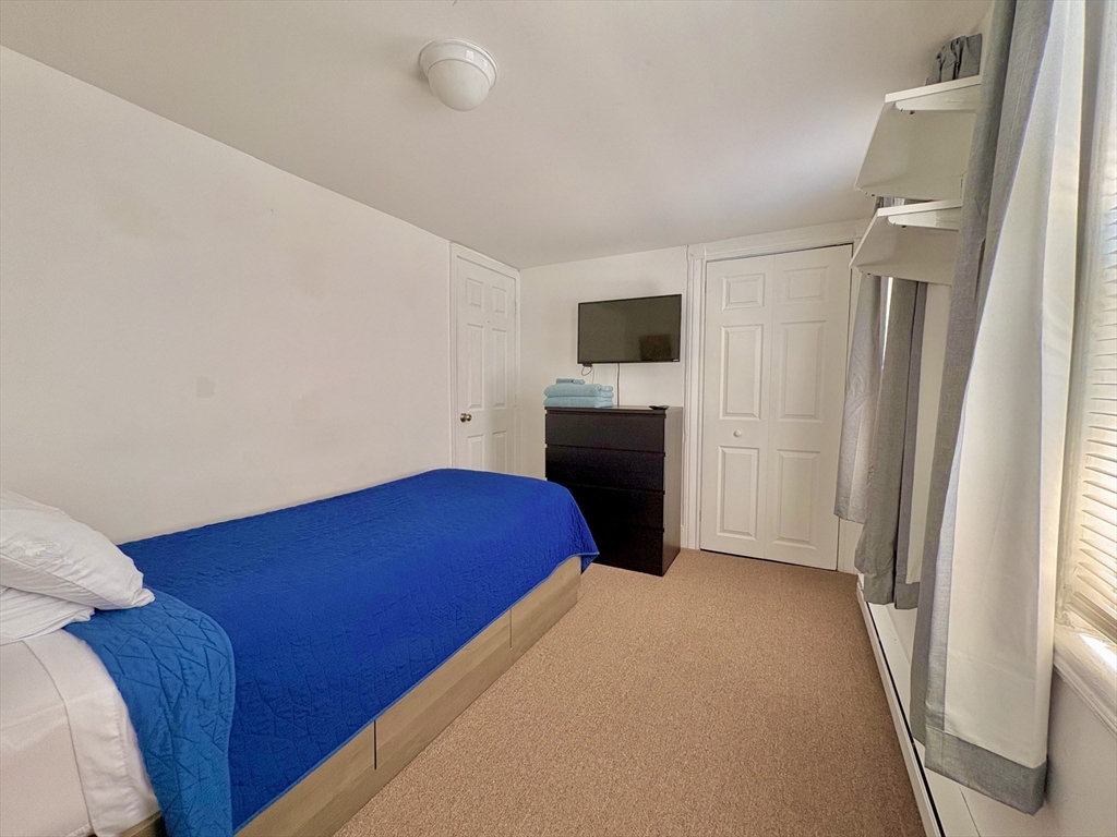 285 Roxbury Street Boston, MA 02119 - Photo 14 of 15 a bedroom with a bed and a flat screen tv