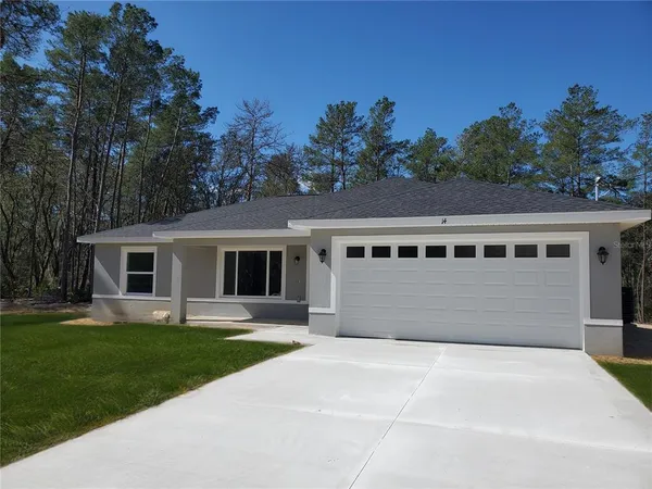 a front view of house with yard and trees in the background