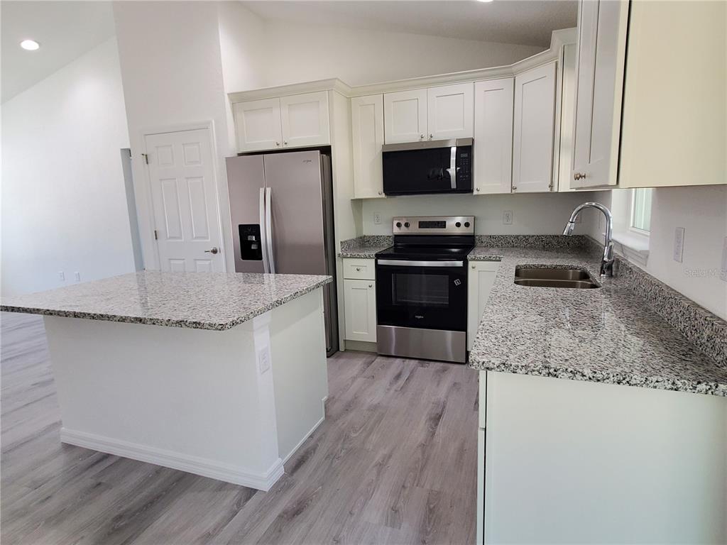 9529 Bahia Road Ocala, FL 34472 - Photo 7 of 20 a kitchen with granite countertop a refrigerator stove and microwave