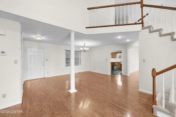 a view of an empty room with wooden floor and a large window