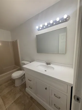 a bathroom with a toilet a sink a light fixture and mirror